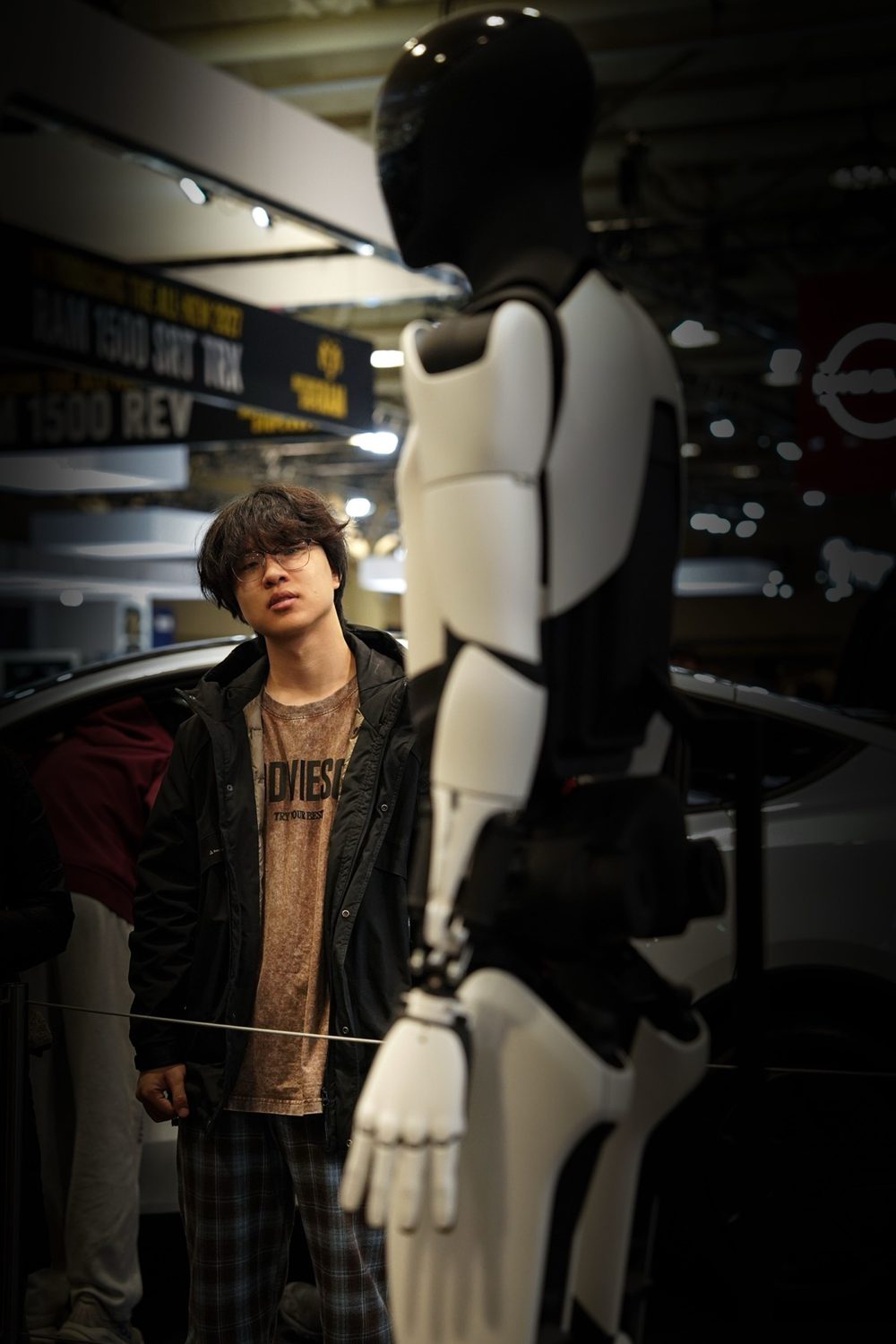 A person closely examining a humanoid robot in a showroom
